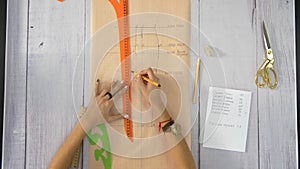 Female hands draw a ruler line on a beige sheet