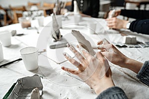 Female hands elegantly shape a small plaster sculpture at a master class.