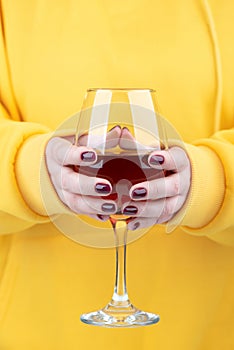 Female hands with fashionable manicure holding a glass of red wine.