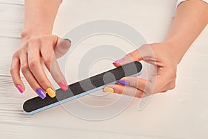 Female hands filing nails with nail file.