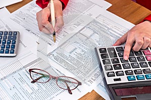 Female hands filling 1040 form and calculating in office