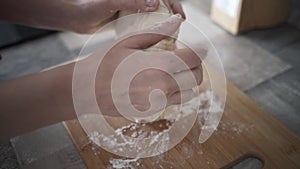 Female hands in flour kneading dough on a wooden board. Action. Close up of woman hands making bread or preparing dough