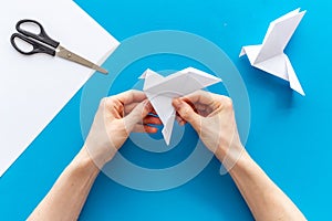 Female hands folding sheet of paper - origami bird. Overhead view