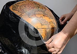 Female hands free an old globe from a black plastic bag.