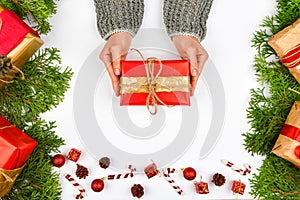 Female hands give a gift top view. Female hands holding a gift with a red bow on a white background with a New Year`s decorator.