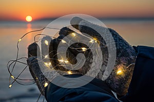 Female hands in gloves hold Christmas lights