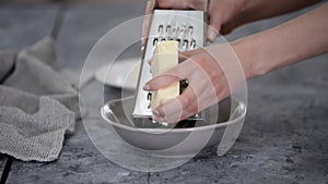 Female hands grate cheese on kitchen.