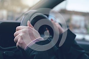 Female hands gripping the steering wheel of a car