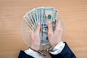 Female hands in handcuffs with dollar.