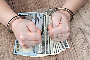 Female hands in handcuffs on dollar banknotes