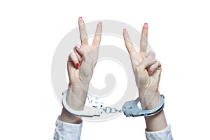 Female hands with handcuffs showing victory sign on white background