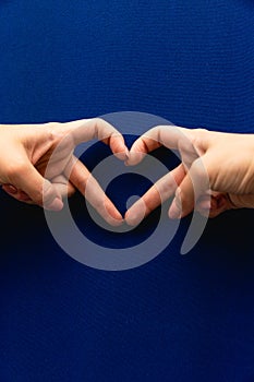 Female hands heart shape on blue background