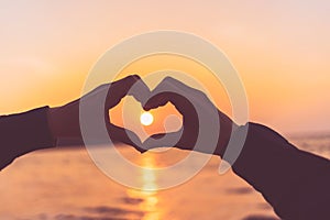Female hands heart shape on sunset sky at tropical beach abstract background. Copy space of happy love travel and freedom in