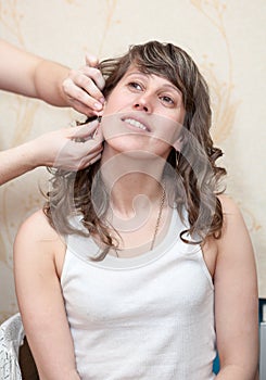 Female hands helps to insert earring in ears, Caucasian bride preparing for wedding at home