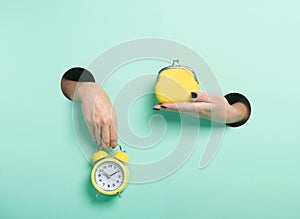 Female hands hold alarm clock and wallet through a hole on neon mint background. Minimalistic creative isolated time is