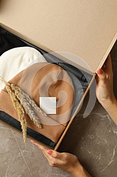 Female hands hold box with different beanies on gray table