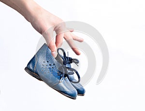 Female hands hold children& x27;s leather boots on a white background.