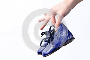 Female hands hold children& x27;s leather boots on a white background.