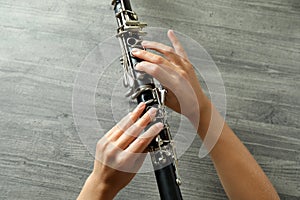 Female hands hold clarinet on gray textured background