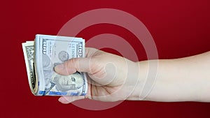 Female hands hold dollars, US currency banknotes on red background, counting a bundle of money, concept of cash, payments, savings