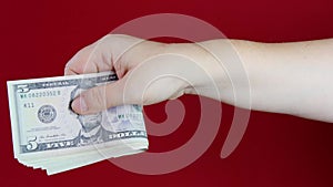 Female hands hold dollars, US currency banknotes on red background, counting a bundle of money, concept of cash, payments, savings