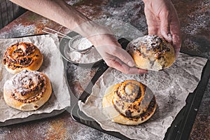 Female hands hold a fresh sweet homemade cinnamon roll with chocolate cream. Scandinavian cuisine. Hyugge style