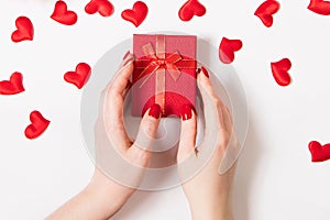 Female hands hold a gift box for valentine& x27;s day. Red roses and candles on a white background.