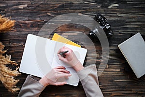 Female hands hold a glass of water, a pen and writes in a notebook business plan top view  business business woman taking notes in