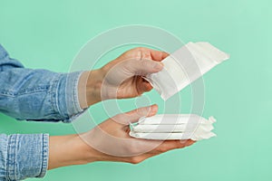 Female hands hold hygiene pads on mint background