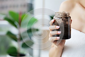 Female hands hold a jar of coffee scrub.