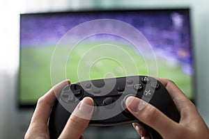 Female hands hold the joystick on the background of the TV, a game of football, close-up, a girl a gamer
