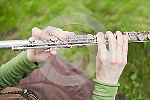 Female hands hold metal flute against green