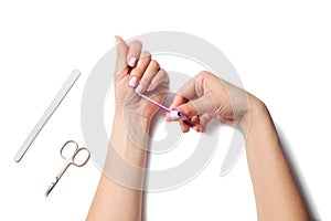 Female hands hold nail scissors, next to lay down devices for nail care. The girl does a manicure. isolated on white background.