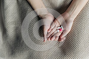 Female hands hold and offer two choice medicine pills capsule for chosen. White and pink candy or meds compare to choose from.