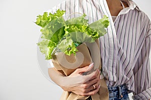 Female hands hold a packet with lettuce on a gray background. Organic food