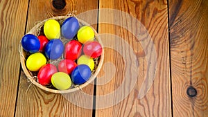 Female hands hold a plate with colorful easter eggs over a wooden table