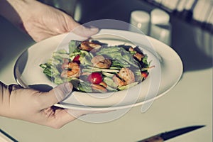 Female hands hold a plate with shrimp salad. The concept of eating and healthy lifestyles