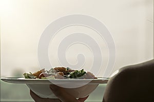 Female hands hold a plate with shrimp salad. The concept of eating and healthy lifestyles
