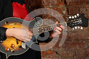 Female hands hold and play mini guitar in studio