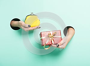 Female hands hold red gift and wallet through a hole on neon mint background. Minimalistic creative isolated sale