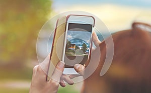 Female hands hold the smartphone while shooting a landscape in N