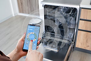 Female hands hold a smartphone with system smart house on a screen on the background of the house