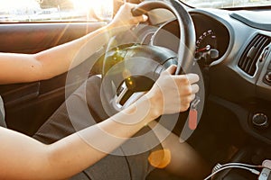 Female hands hold the steering wheel, close-up. A woman is driving a car. Toned.