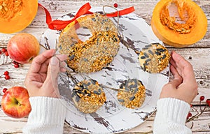 Female hands hold treats for wild birds in winter. Homemade pumpkin feed, bacon, millet, seed on a white wooden