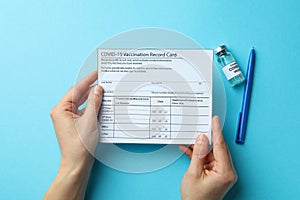 Female hands hold Vaccination record card on blue background