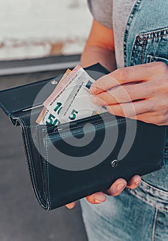 Female hands hold a wallet with euro banknotes. The concept of finance, savings, financial expenses. Close-up. Vertical shot