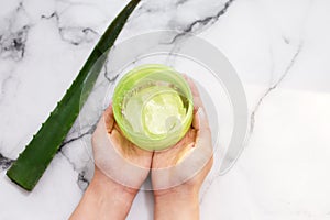 Female hands holding aloe gel on marble background