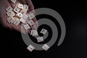 Female hands holding alphabet toy blocks on black background