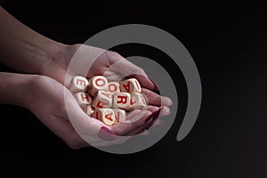 Female hands holding alphabet toy dices on black background