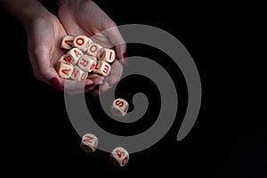 Female hands holding alphabet toy dices on black background and copy space